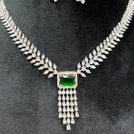 Diamond necklace set featuring a radiant green color stone centerpiece framed by diamond leaves and cascading diamond drops on a mannequin bust.