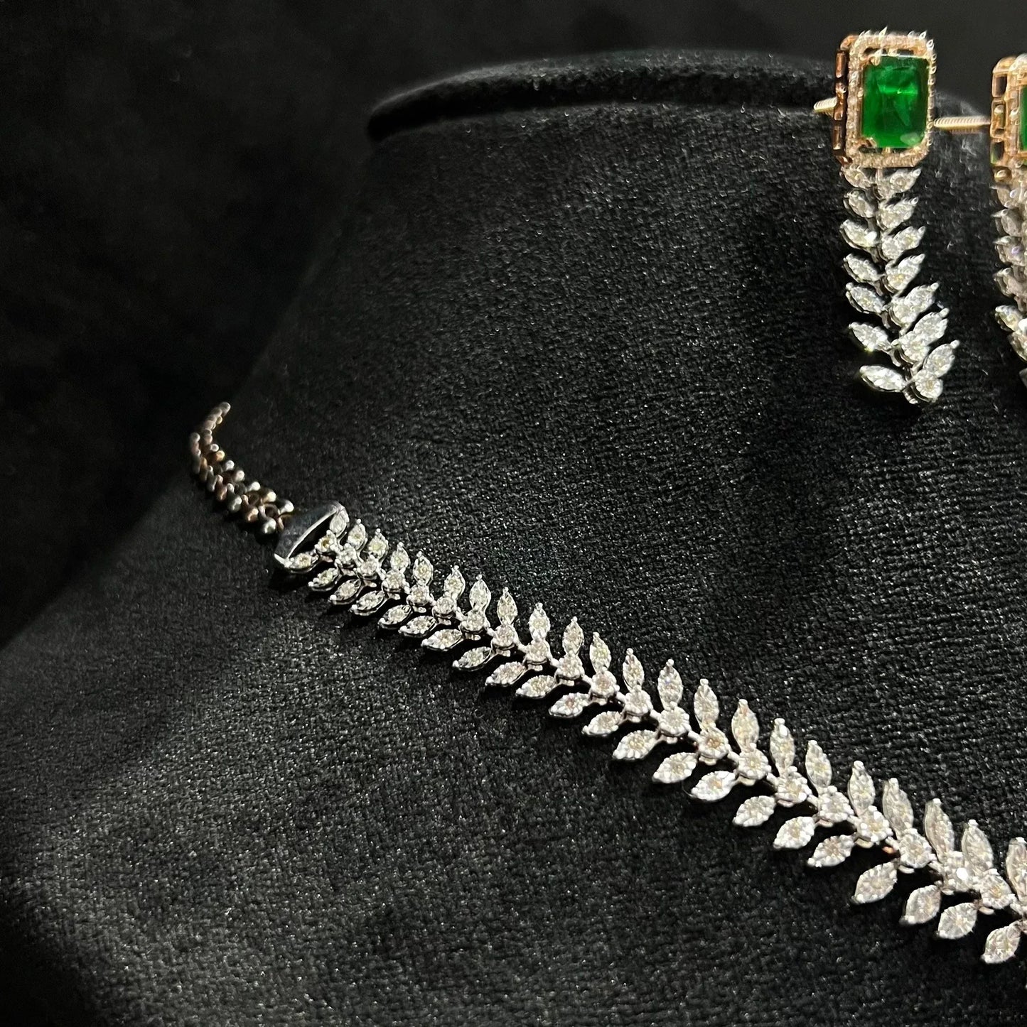 Diamond necklace set framed by diamond leaves and cascading diamond drops, paired with matching earrings on a mannequin bust from right side.