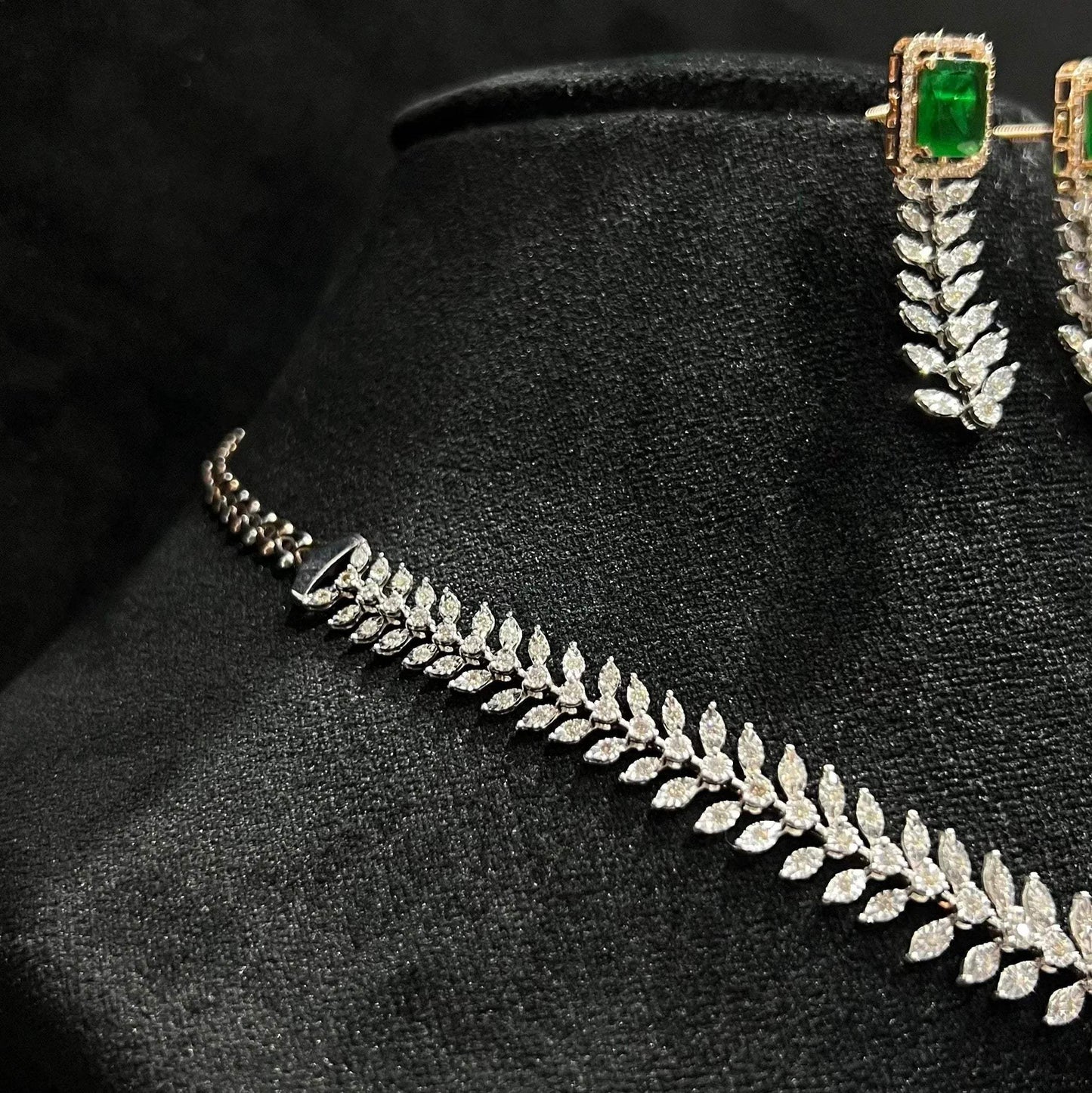 Diamond necklace set framed by diamond leaves and cascading diamond drops, paired with matching earrings on a mannequin bust from right side.