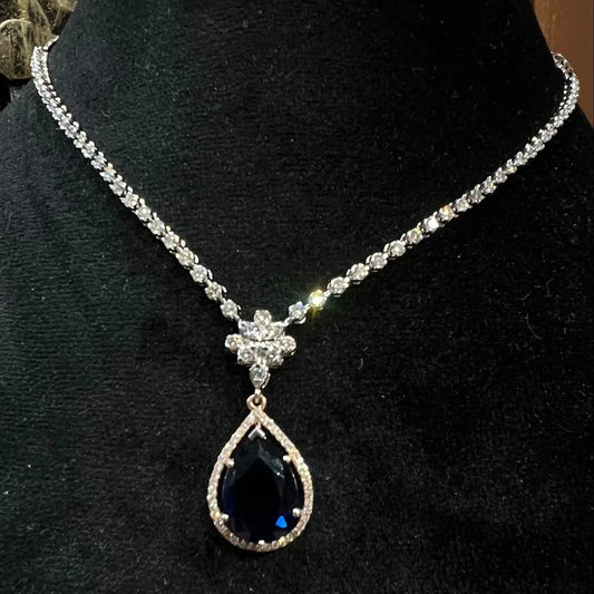 Elegant diamond necklace set with teardrop color stone pendant on black display