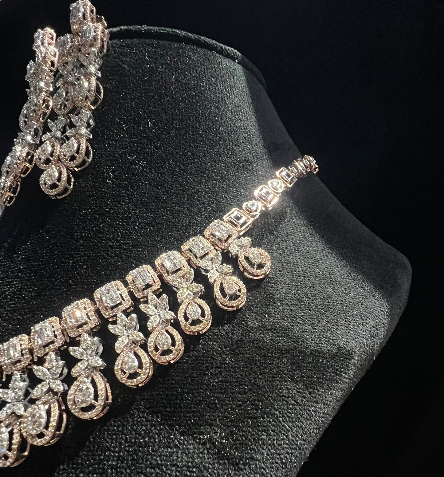 Luxury floral motif diamond necklace set with matching drop earrings on a mannequin bust.