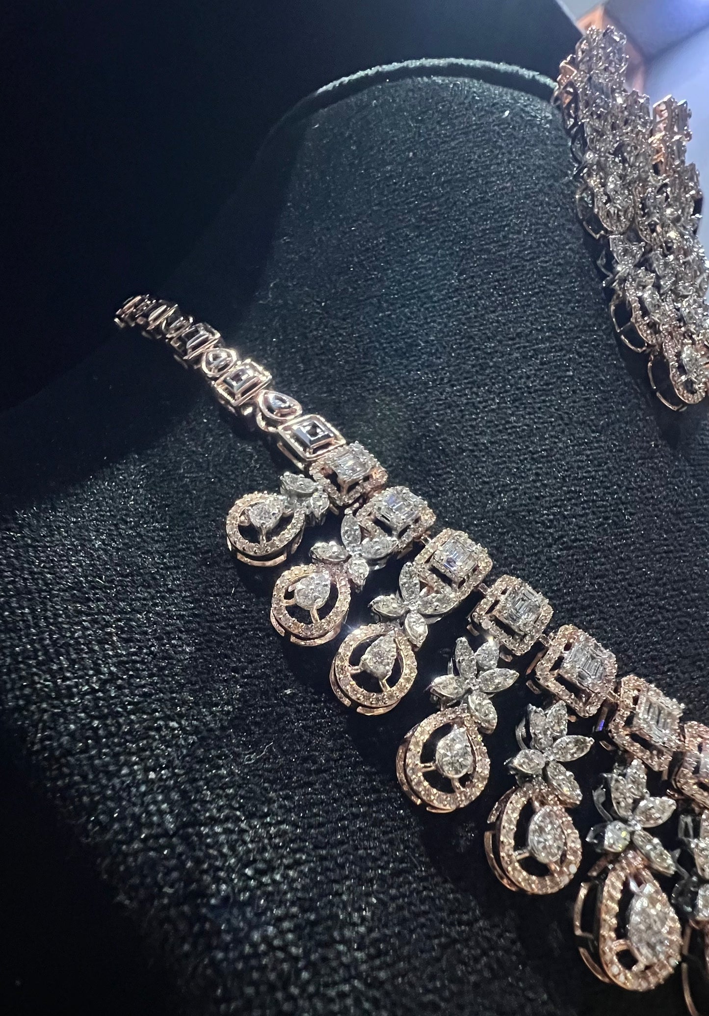 Luxury floral motif diamond necklace set with matching drop earrings on a mannequin bust.