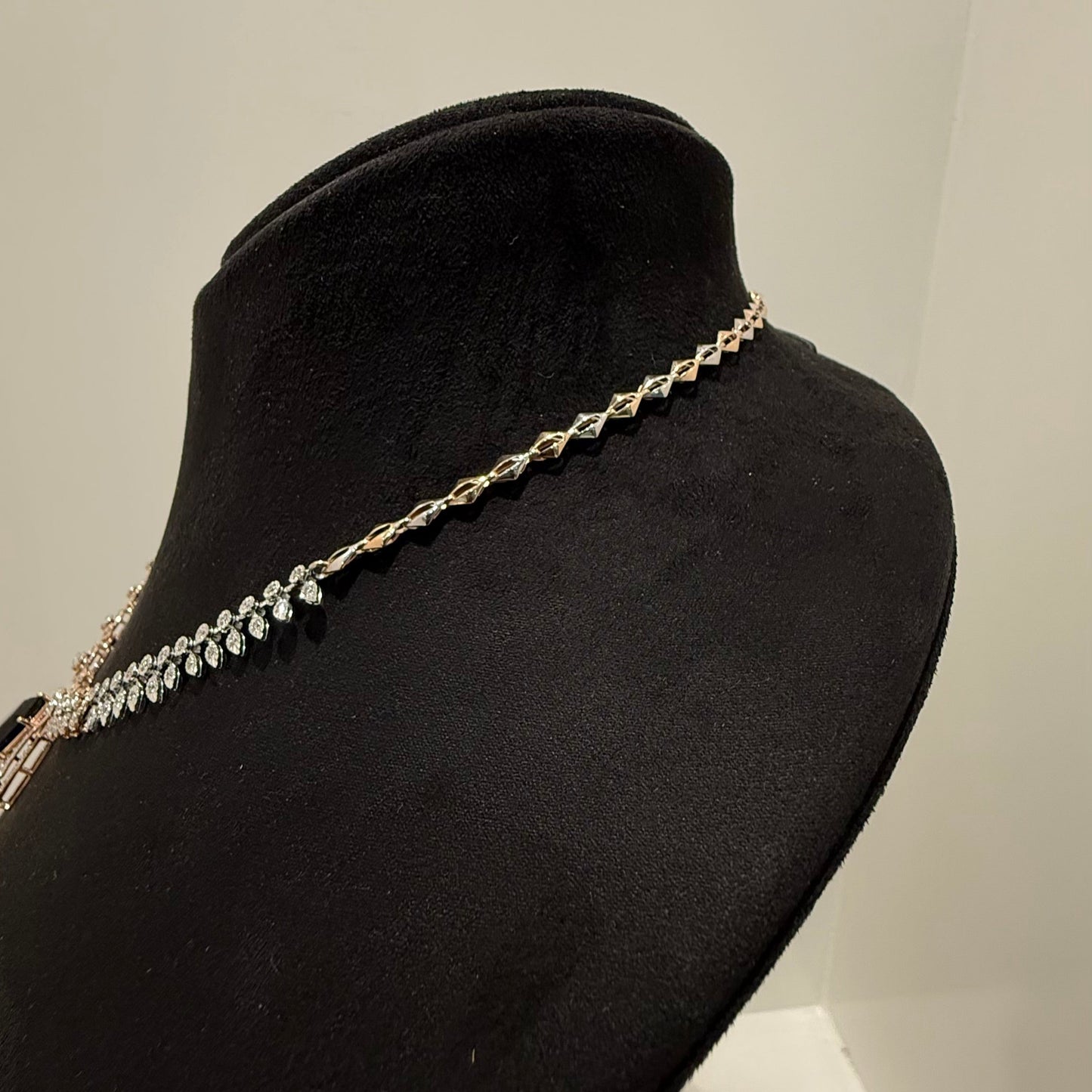 A gold diamond necklace displayed on a mannequin bust from back side.