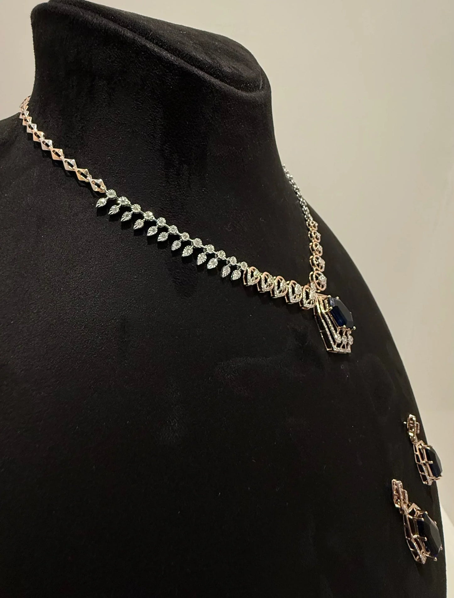 A gold diamond necklace with a geometric pendant and matching earrings displayed on a mannequin bust from right side.