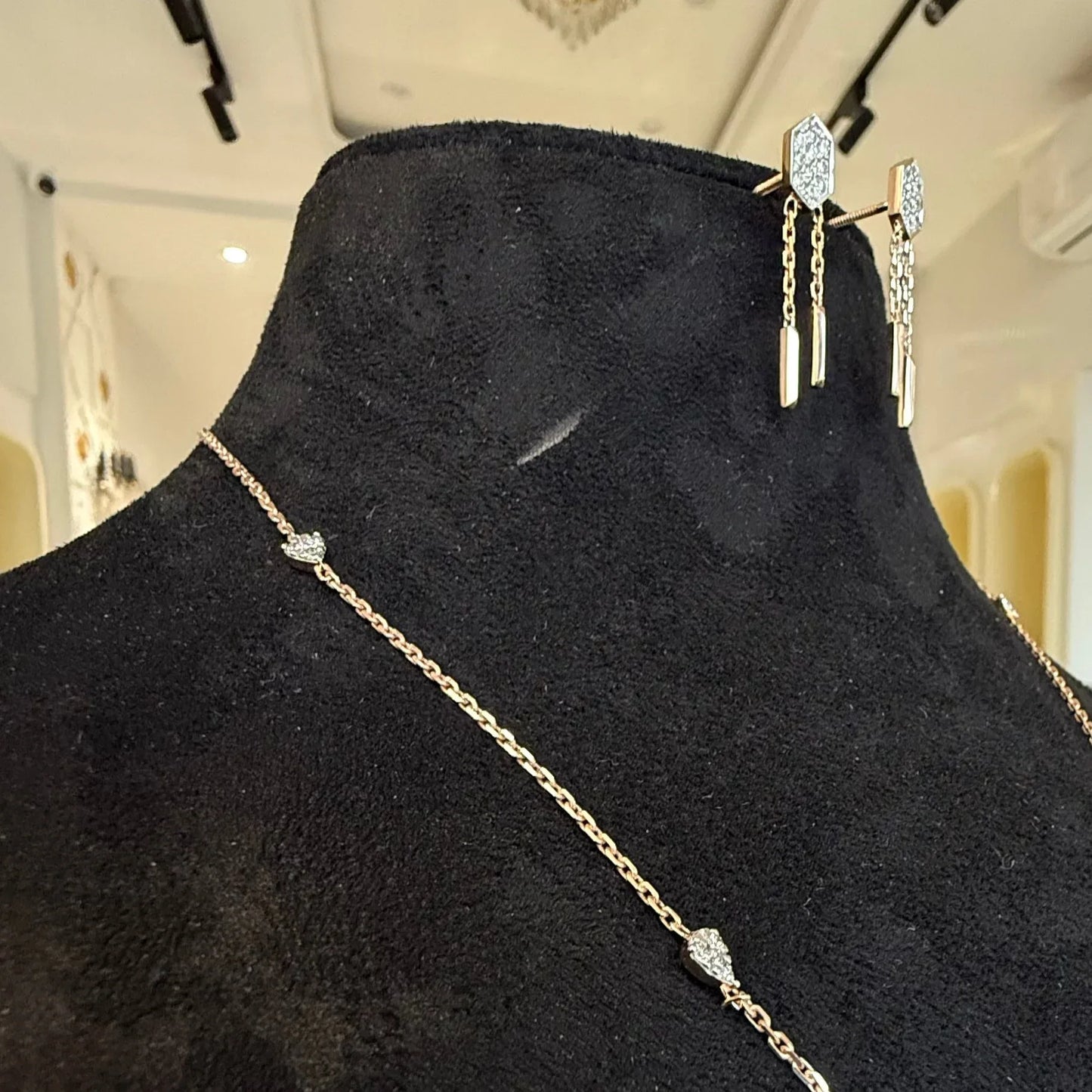 Modern diamond necklace set with hexagon pendant and matching drop earrings on display.