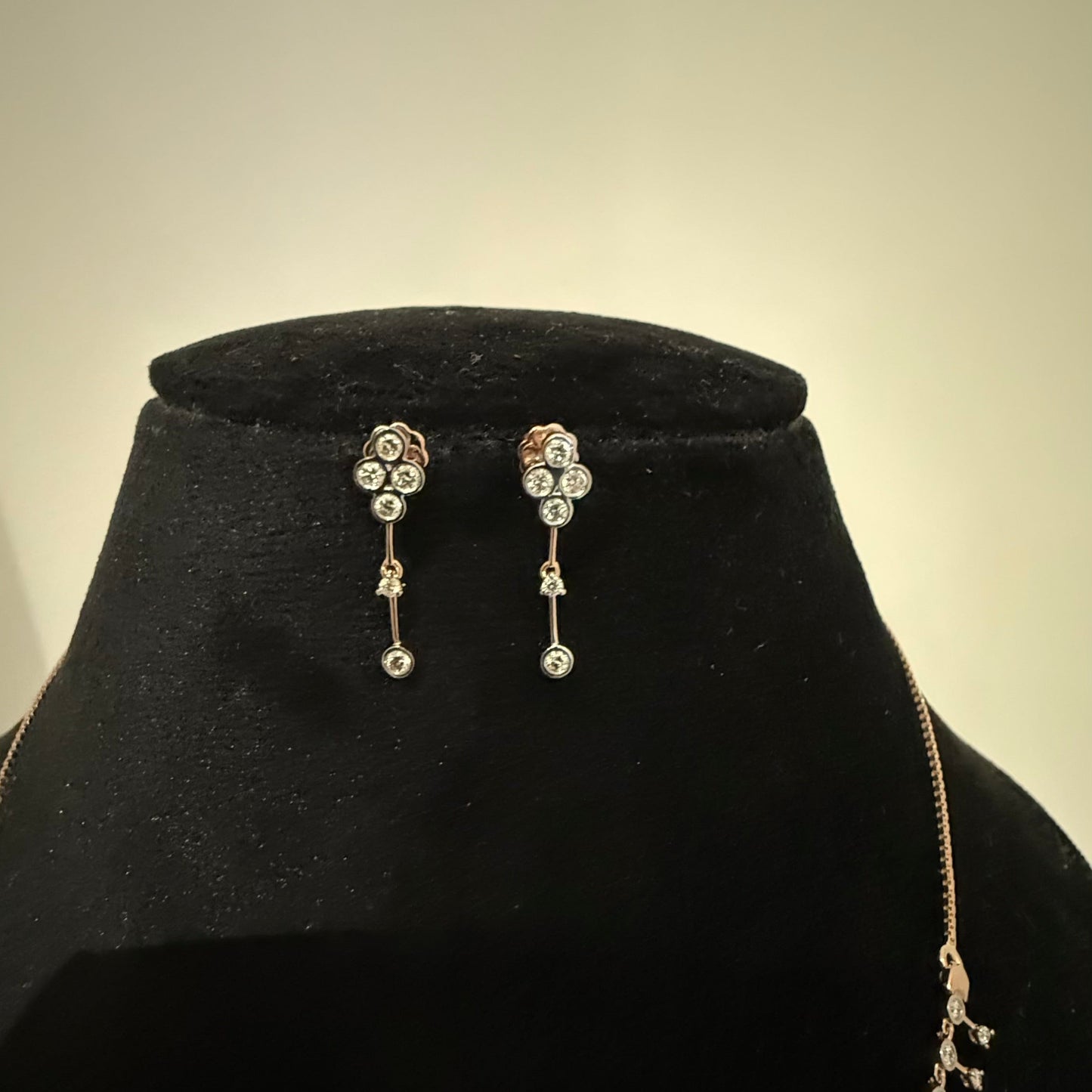 A mannequin showcasing a minimalist diamond necklace and earrings set in gold.