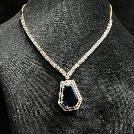 A diamond necklace set featuring a striking geometric deep blue gemstone pendant, all displayed on a black velvet background.