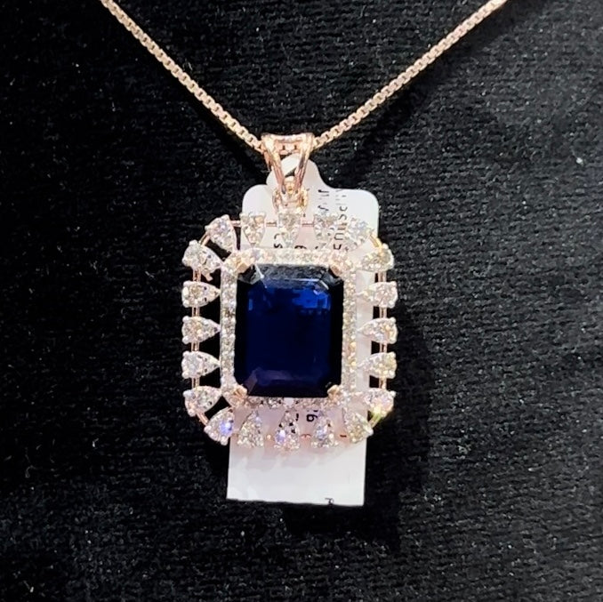 A gold diamond pendant with a blue center stone surrounded by smaller white diamonds, attached to a gold chain for earrings.
