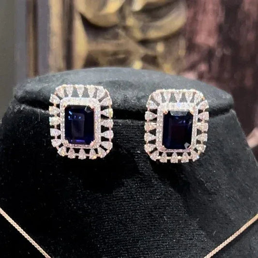 gold diamond earrings with a blue center stone surrounded by smaller white diamonds