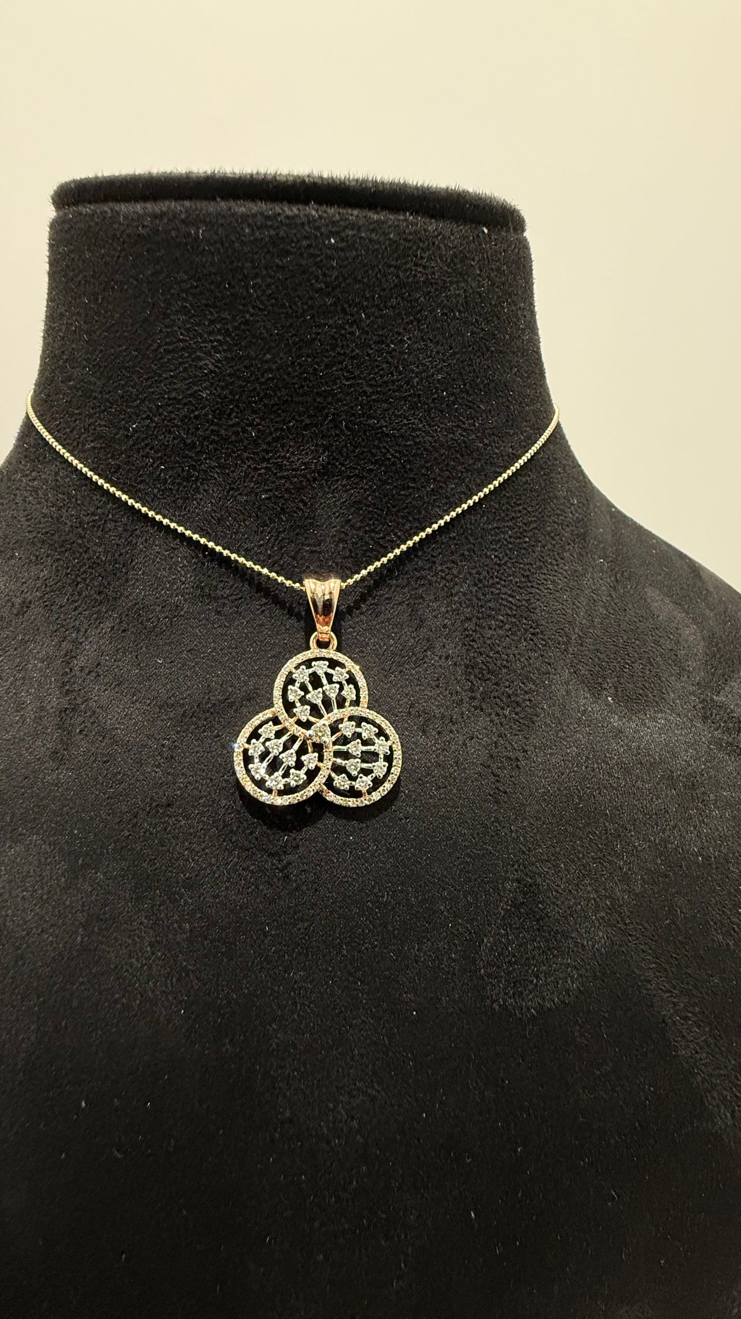 A gold diamond pendant with a floral design, displayed on a black mannequin necklace stand.