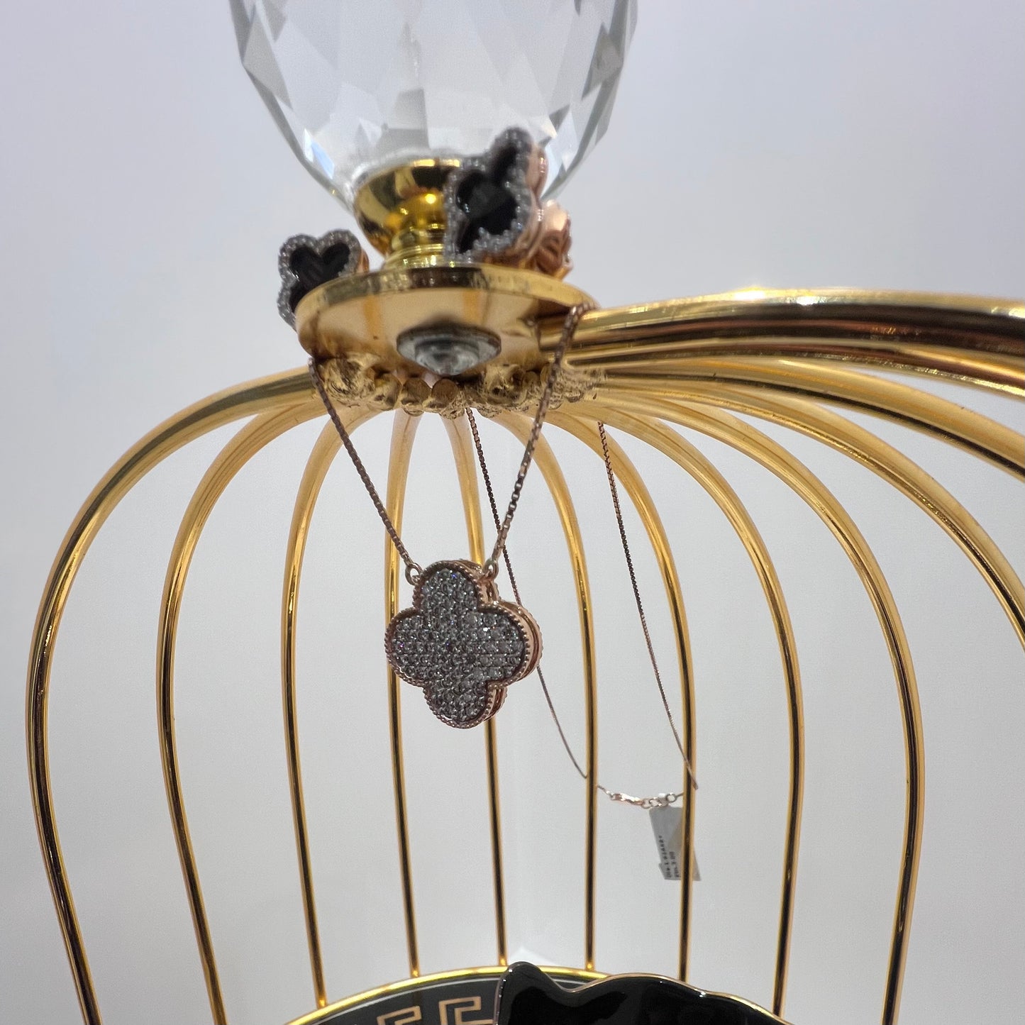 A gold diamond pendant with earrings set, featuring a chain of inset diamonds on a gold-colored metal structure, displayed on a glass stand.