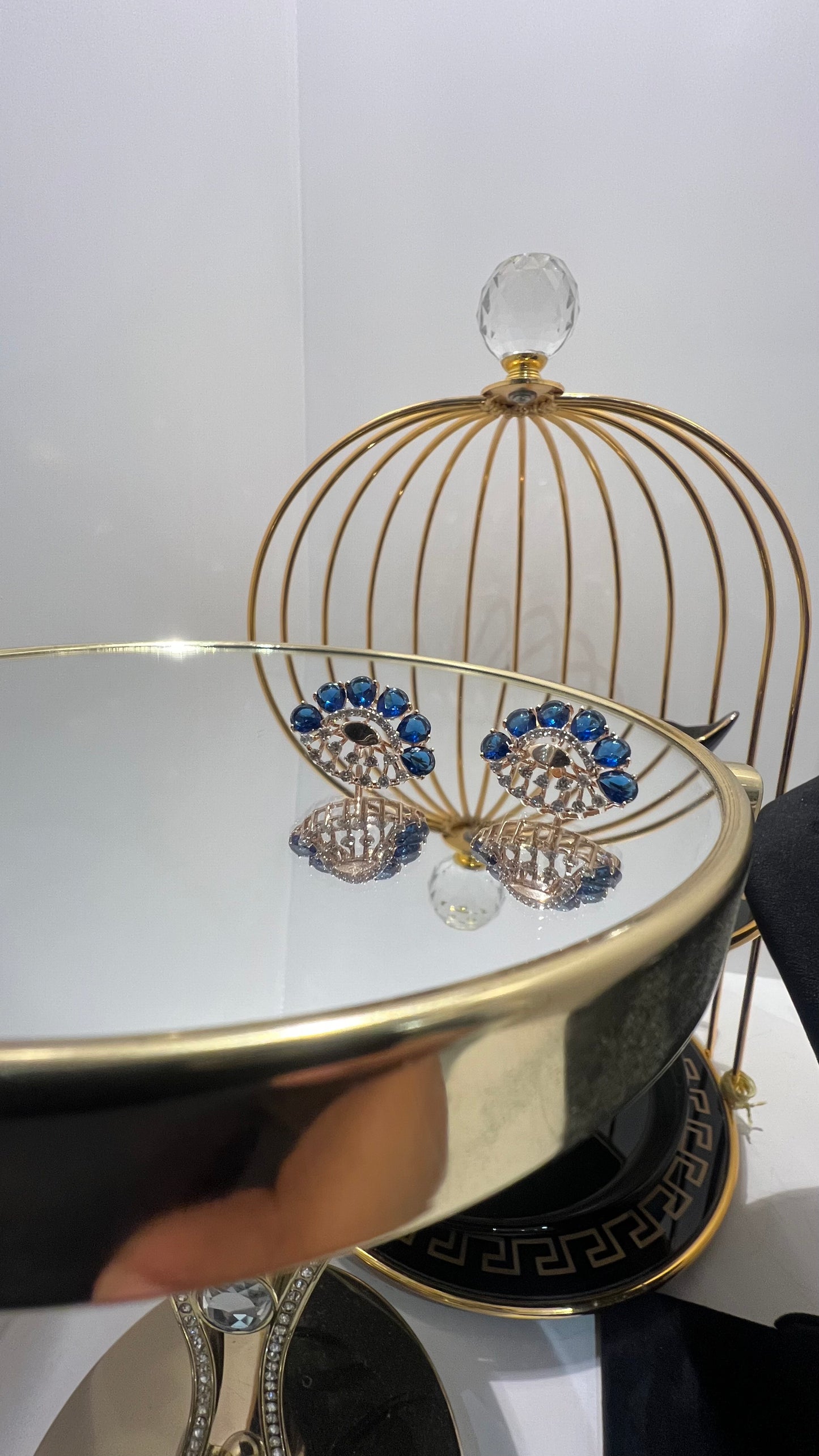 gold diamond earrings with blue stones, displayed on a table.