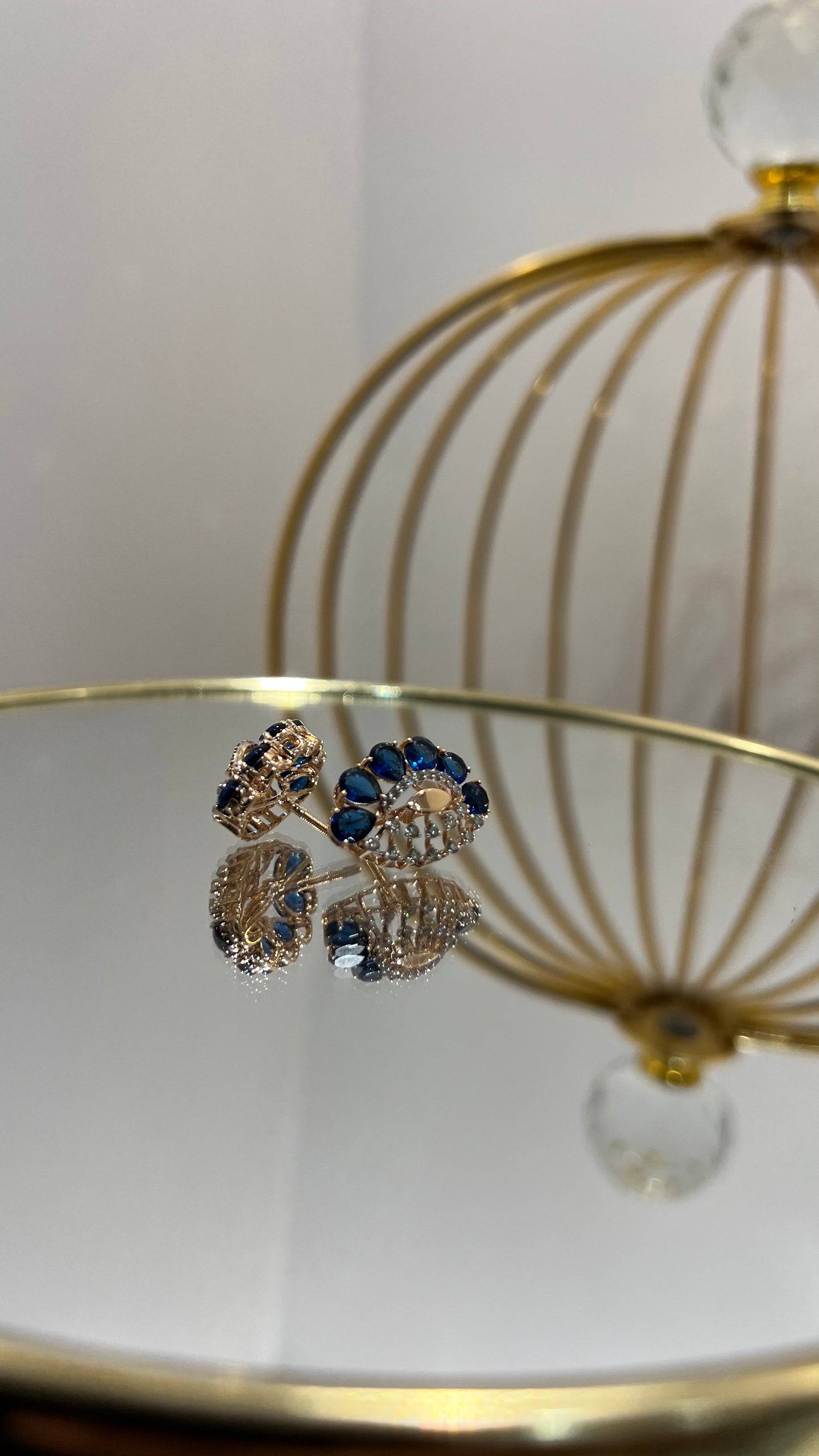 gold diamond earrings with blue stones, displayed on a table.
