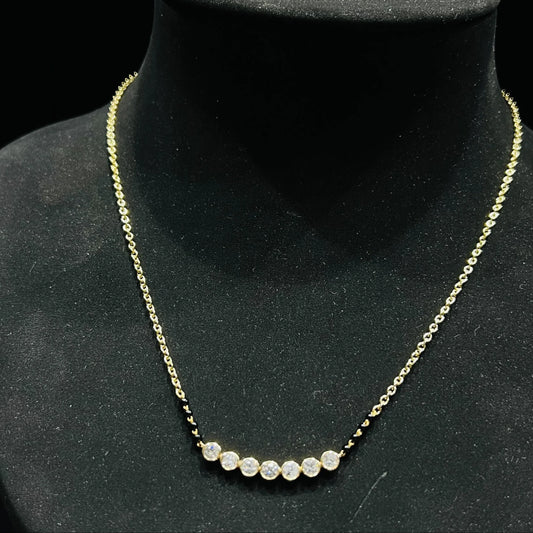 A stylish gold diamond beaded mangalsutra with seven round bezel-set diamonds in a row, paired with small black beads on a delicate gold chain.