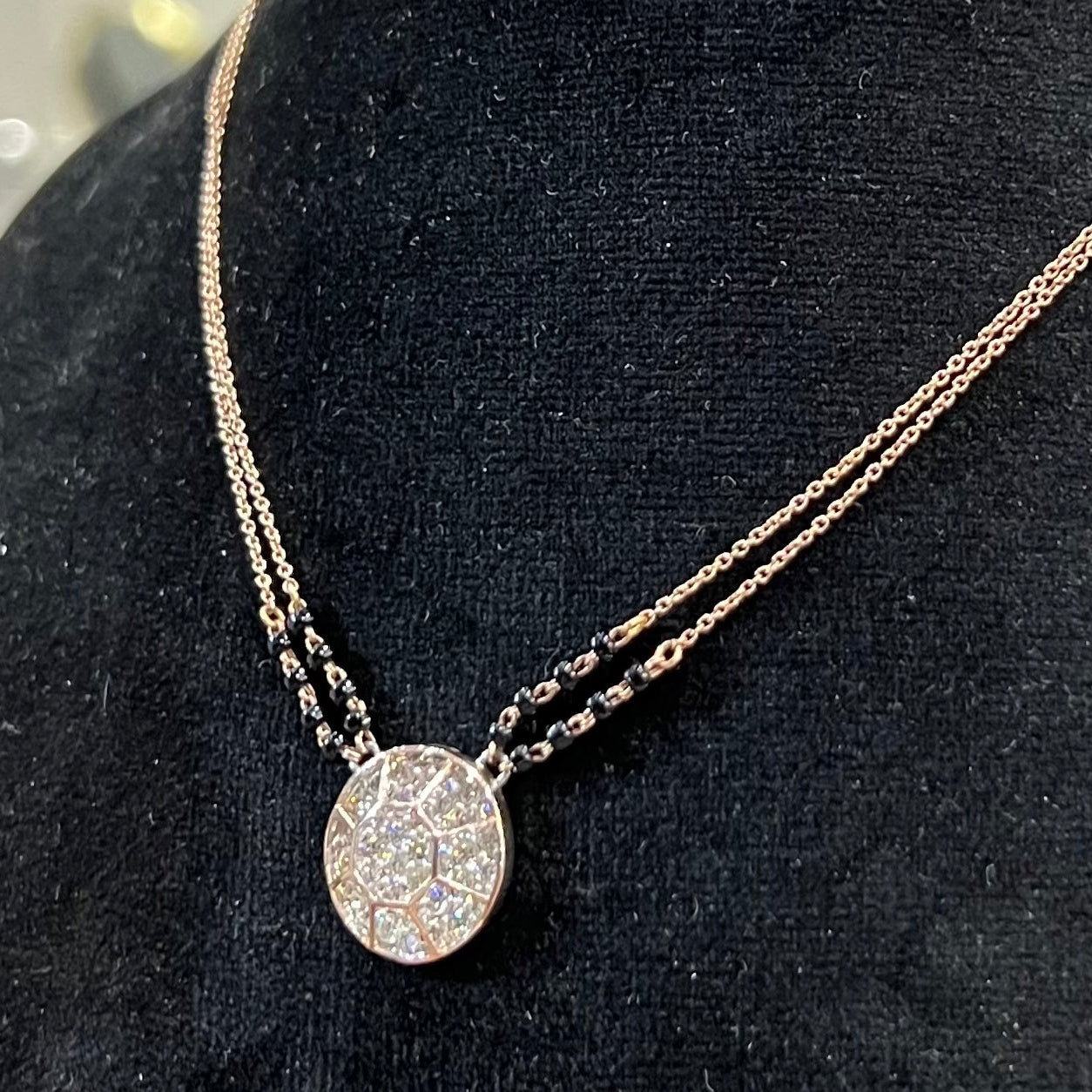 Elegant gold diamond mangalsutra with a circular diamond-studded pendant in honeycomb design, paired with black bead and gold chain for a modern traditional look.