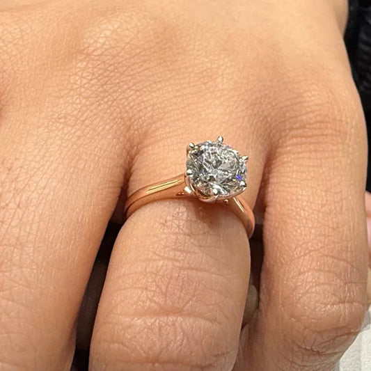 A classic solitaire lab grown diamond ring with a round-cut diamond set in a four-prong gold band, displayed worn in a hand's finger.