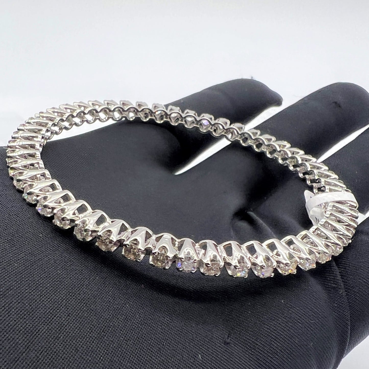 White gold bangles with lab grown diamonds on a black glove with a white background.