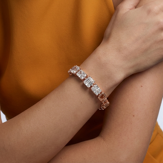 Rose gold bracelet with lab grown diamonds on a wrist against an orange background
