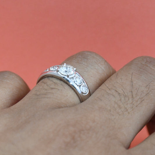 White gold ring with lab diamonds on a finger against a pink background