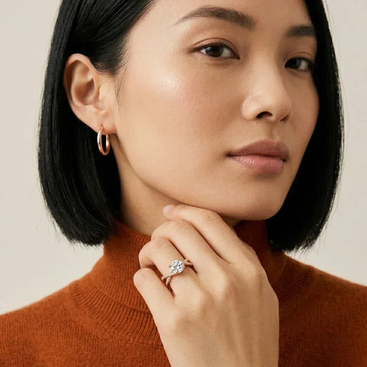 Woman wearing a ring with a solitaire lab grown diamond and some other small lab grown diamonds, close-up of face and hand.