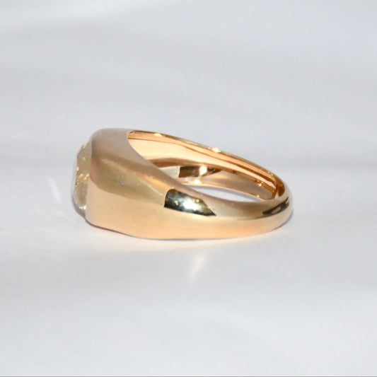 A gold ring with natural sapphire gemstone is displayed on a white surface.