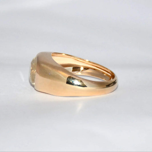 A gold ring with natural sapphire gemstone is displayed on a white surface.