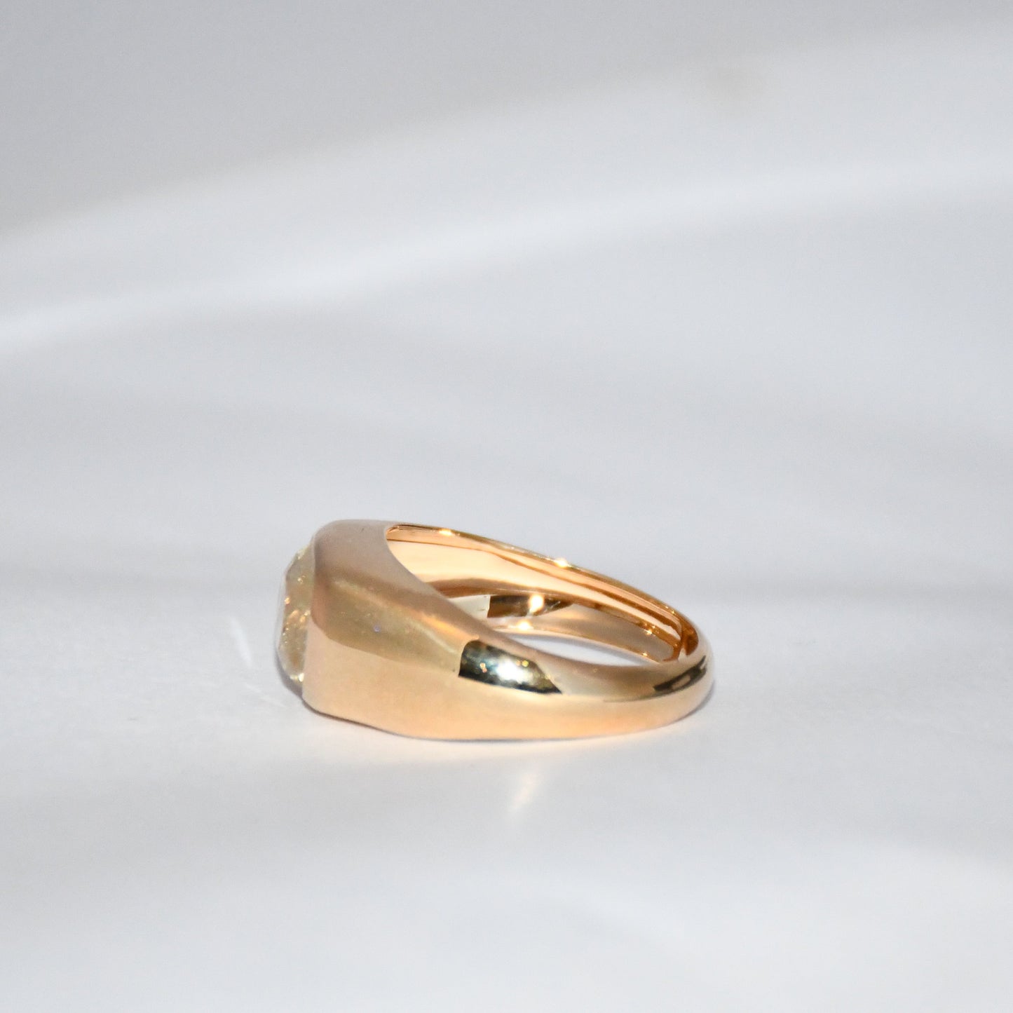 A gold ring with natural sapphire gemstone is displayed on a white surface.