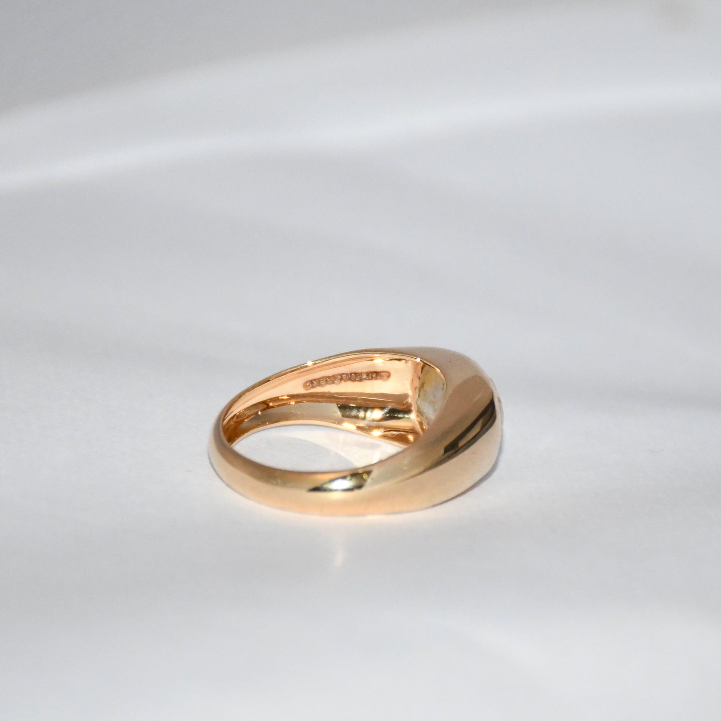 A gold ring with natural sapphire gemstone is displayed on a white surface.