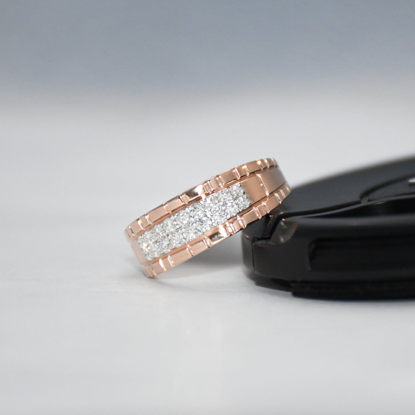 gold ring with diamonds on a black stand against a gray background
