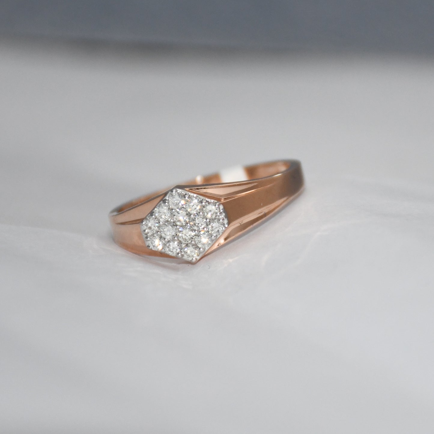gold ring with diamond hexagonal design on a light gray background