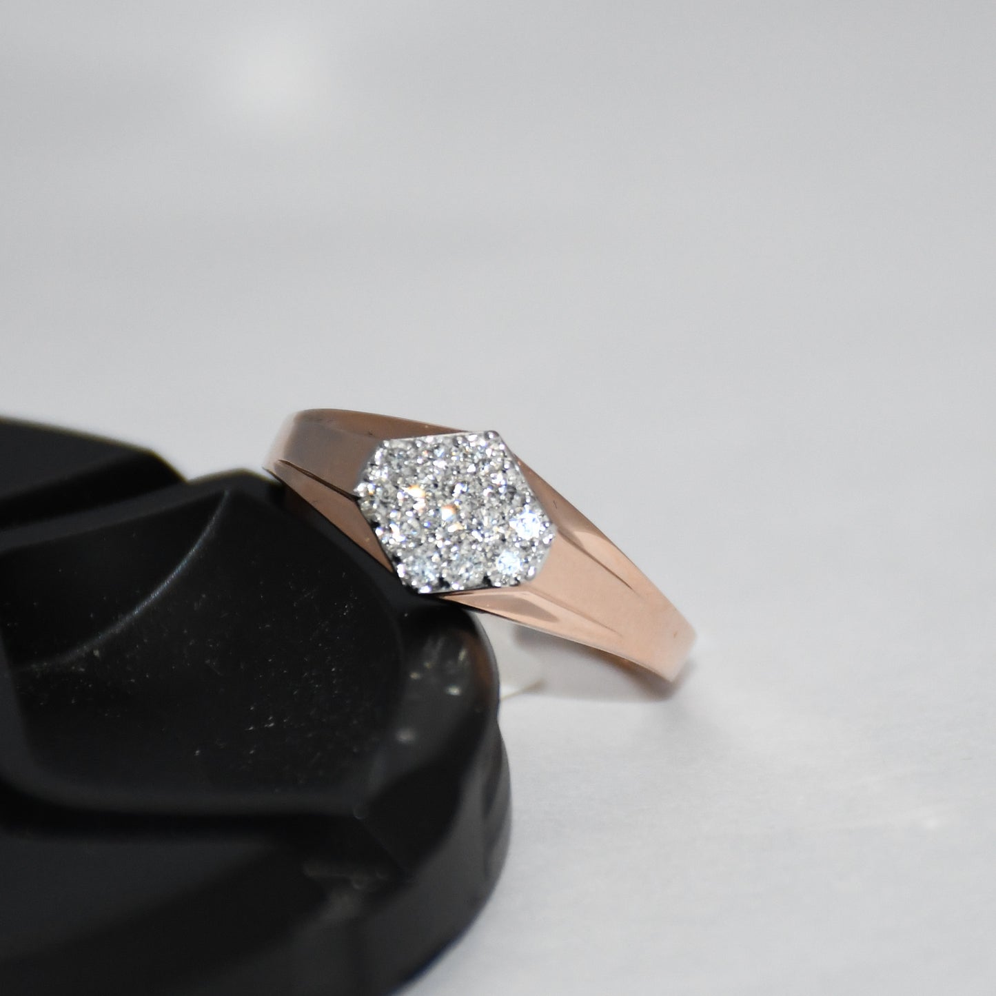 gold ring with diamond accent on a black stand against a light gray background
