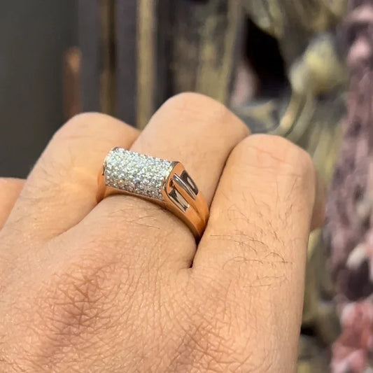 A man's hand holding a diamond men's ring with a gold band, featuring prominent diamonds centerpiece.