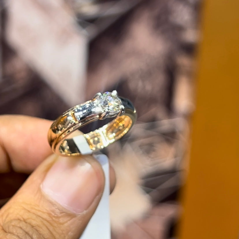 A man's hand holding a diamond solitaire ring with a gold ring.