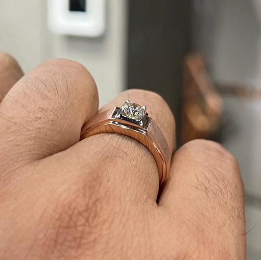A man's hand displaying a solitaire men's diamond ring with a gold band.