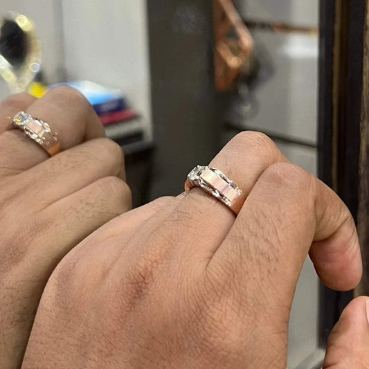 A man's hand holding a diamond solitaire ring with a gold band against a mirror.