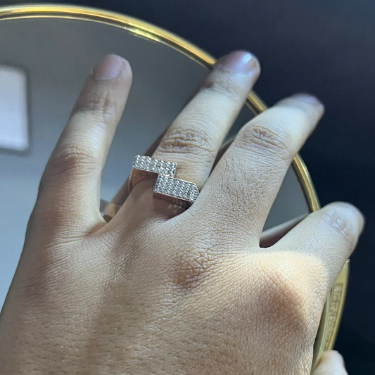 A man's hand displaying a 14K gold diamond ring with a solid band and a small diamond inlay on the top surface.