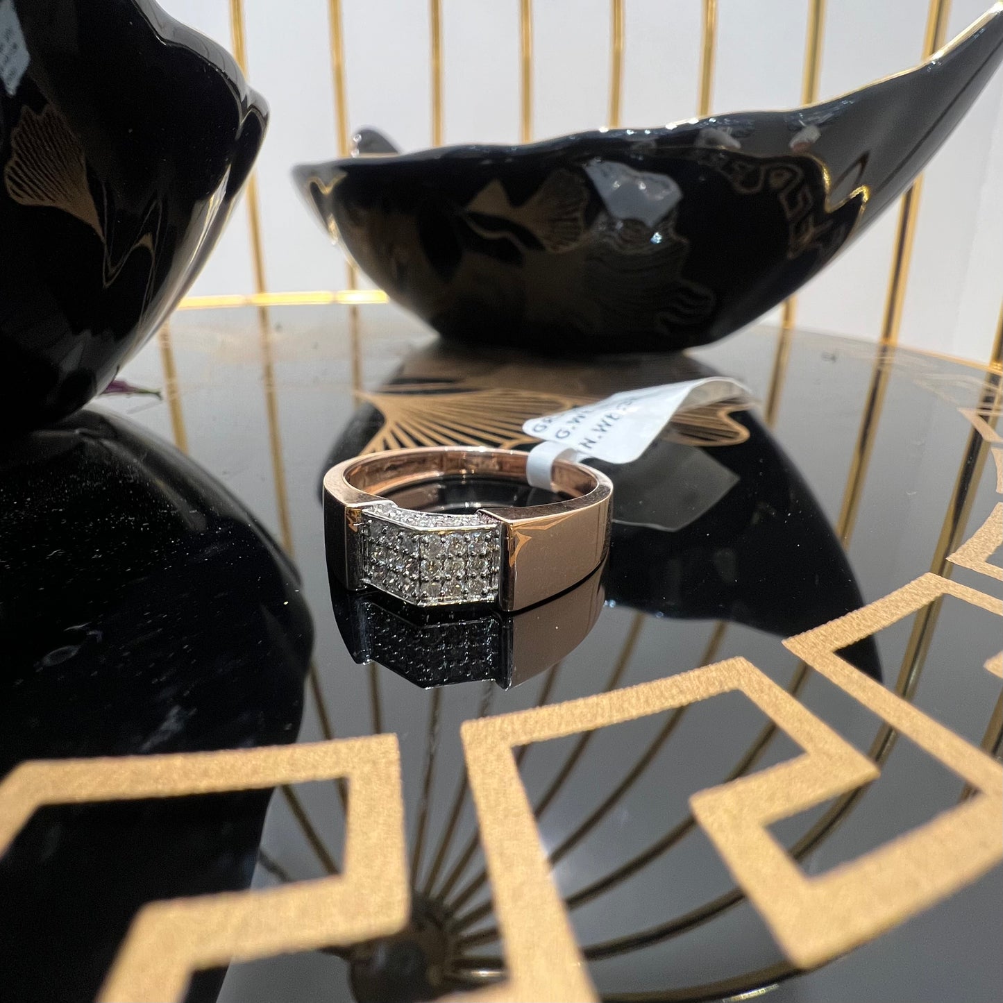 A man's hand holding a gold-banded ring with a large, clear crystal on top, and a smaller, real diamond on the band.