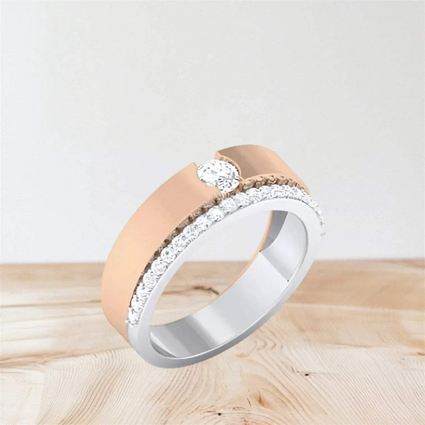 Two-tone diamond ring with rose gold and white gold band on a light wooden surface