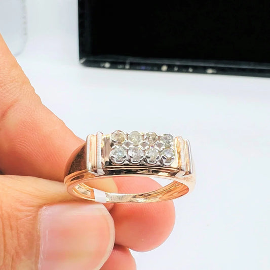 A man's hand displaying a gold diamond ring with round cut diamonds.