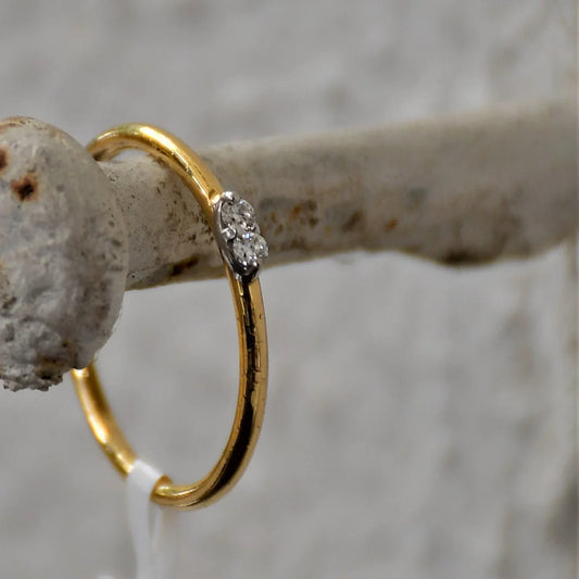 A gold band ring with two diamonds set on top, positioned on hanger.