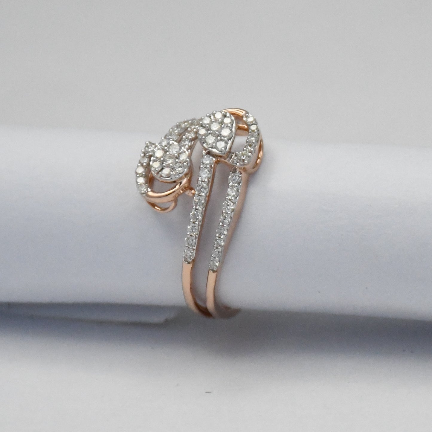 Rose gold ring with diamonds on a light gray background