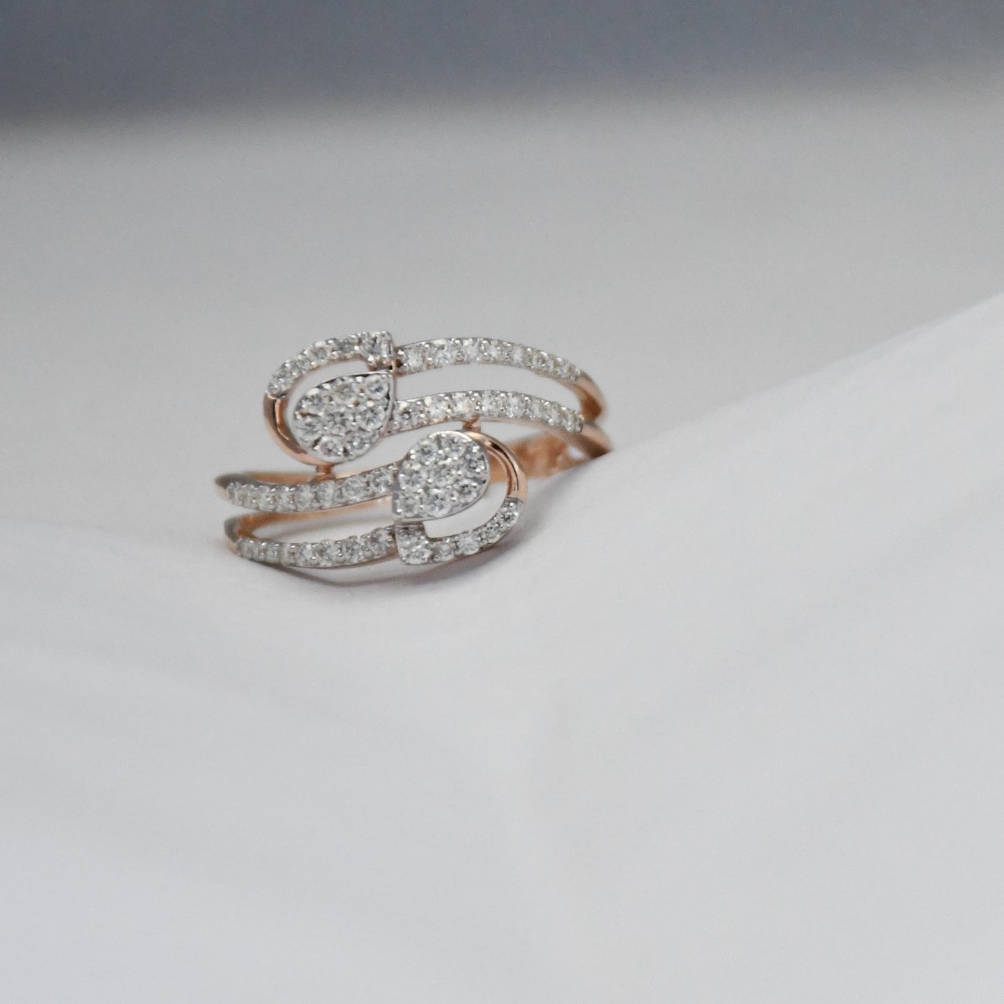 Rose gold ring with diamonds on a light gray background