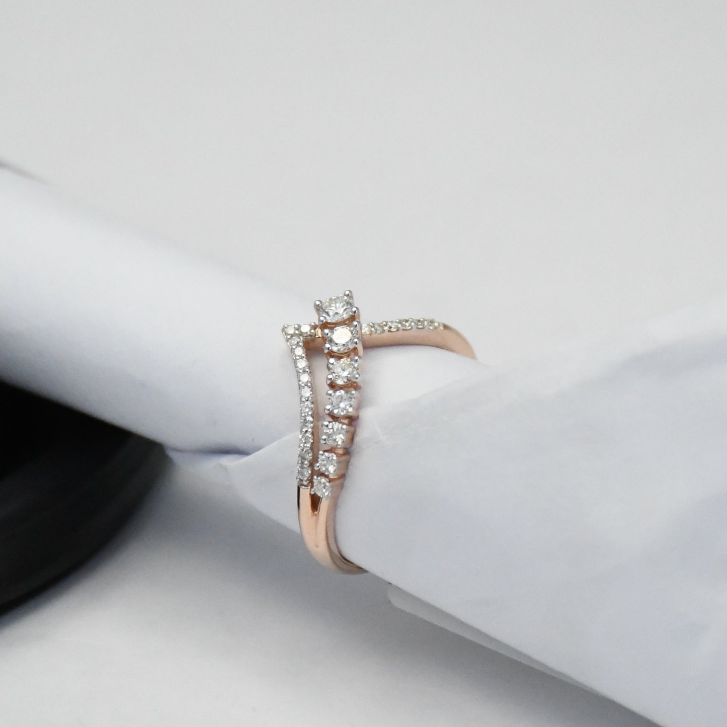 Rose gold ring with diamonds on a white surface