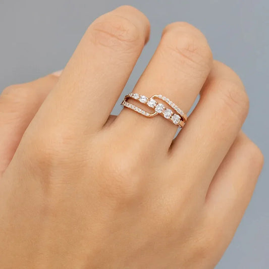 Hand wearing a gold ring with diamonds on a gray background