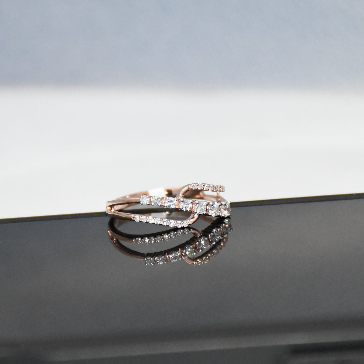 gold ring with diamonds on a reflective surface