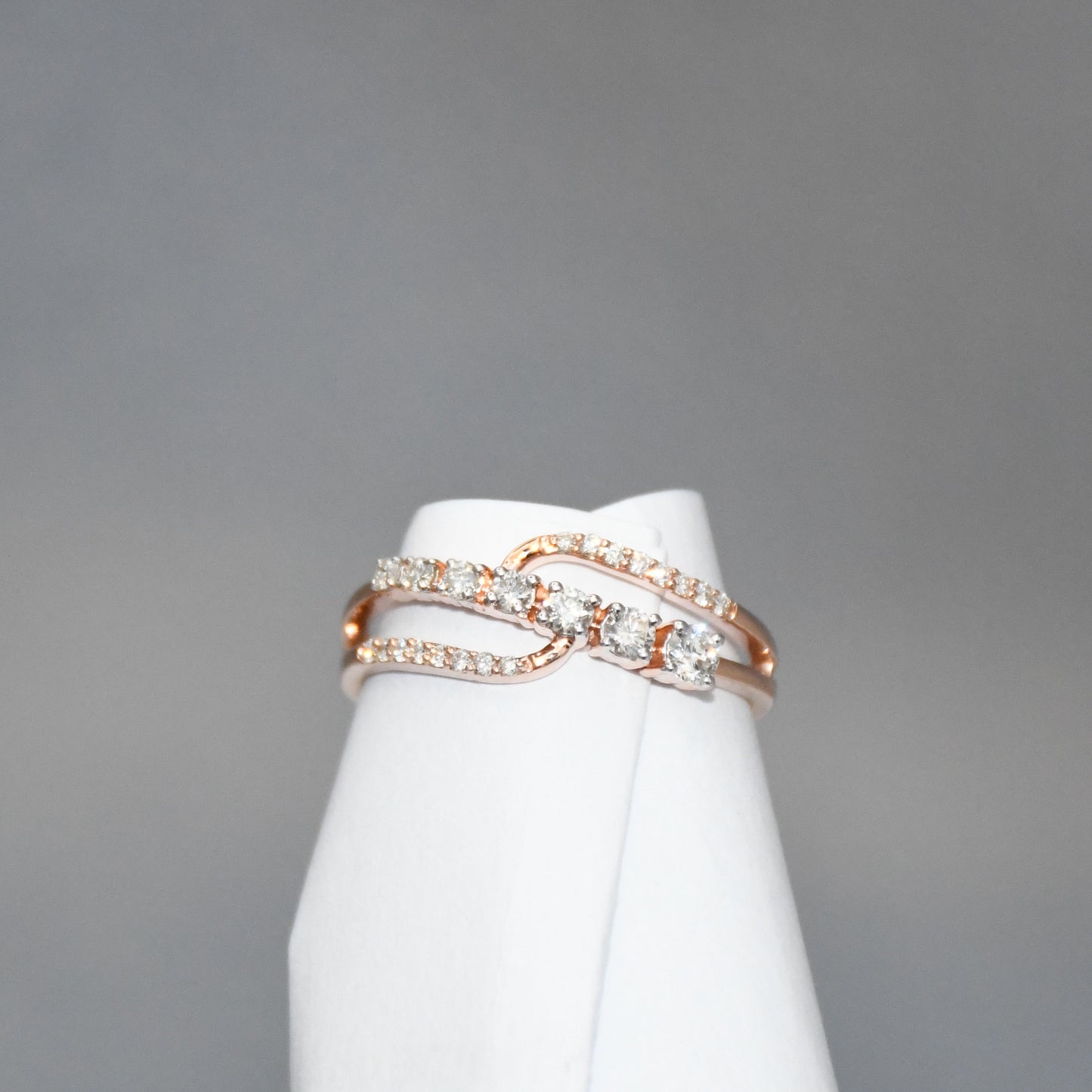 gold ring with diamonds on a white stand against a gray background