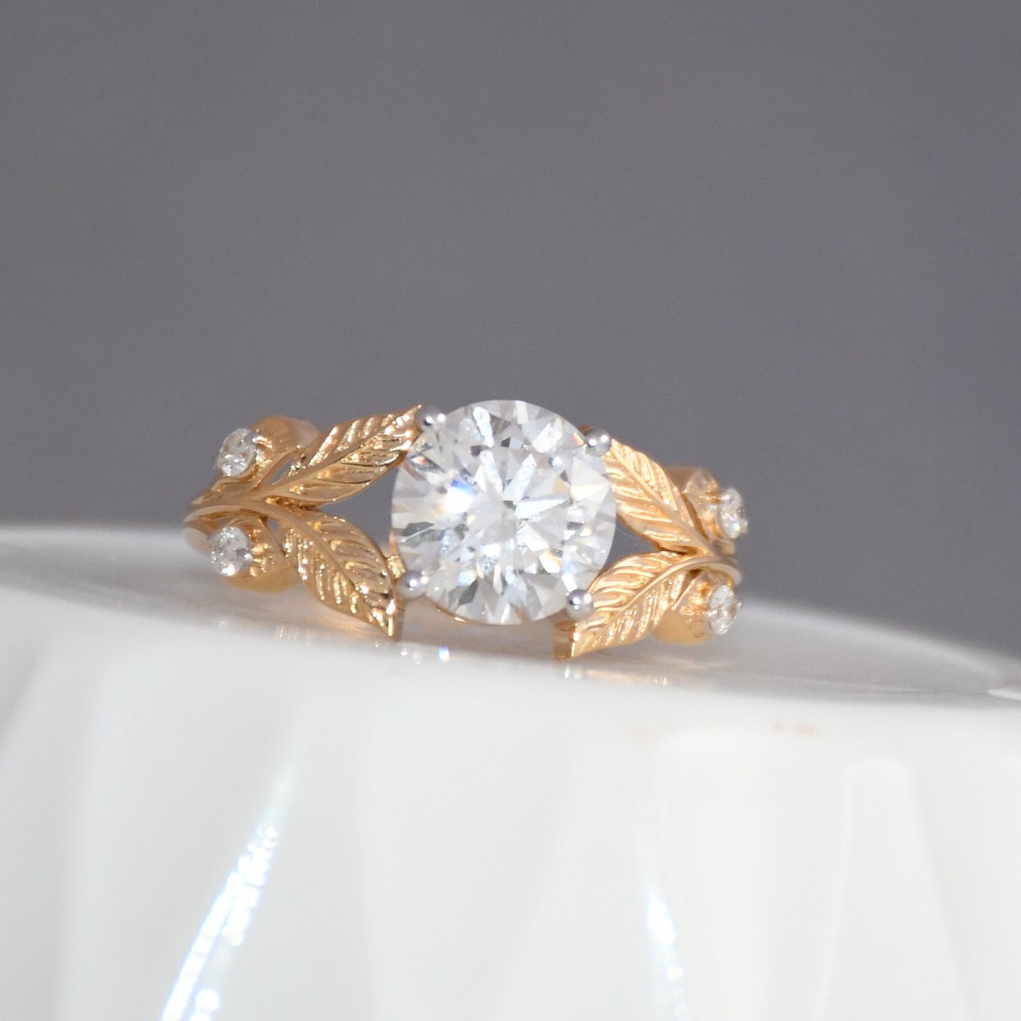 Gold ring with a diamond on a white surface and gray background