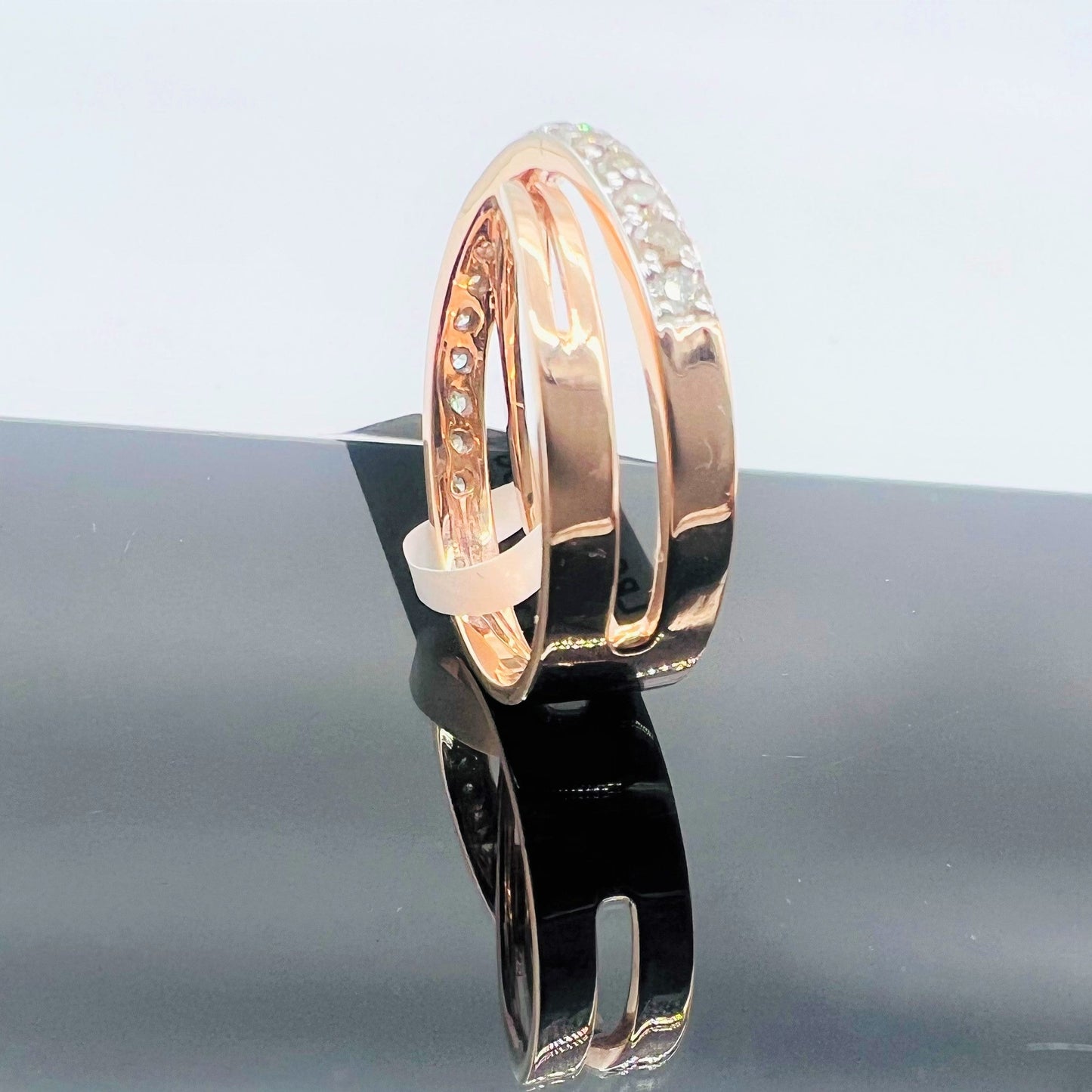 A diamond band ring with 14K gold hallmark, displayed on black reflective surface.