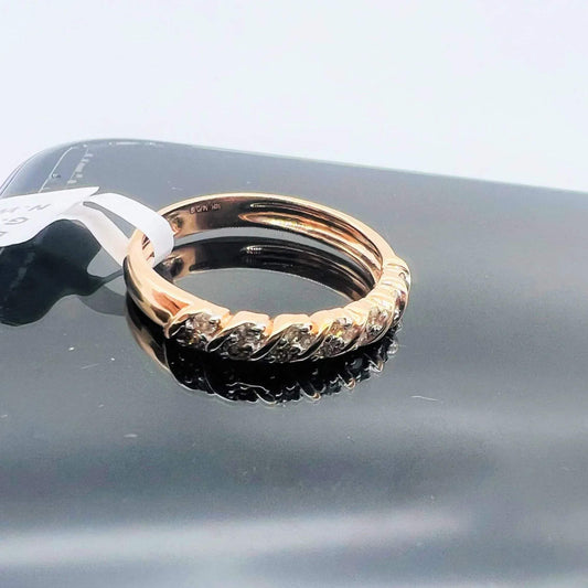 A 14K gold hallmark ring with certified diamonds set around its circumference is displayed on a reflective surface.