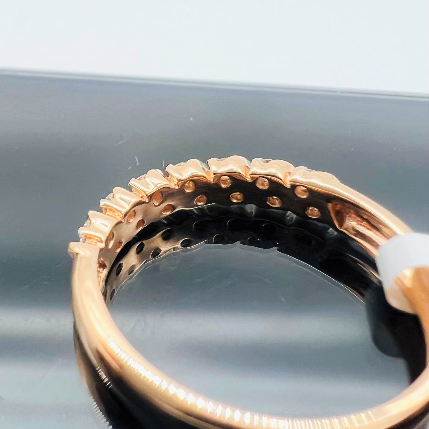 A 14K gold hallmark ring with certified diamonds set around its circumference is displayed on a reflective surface.